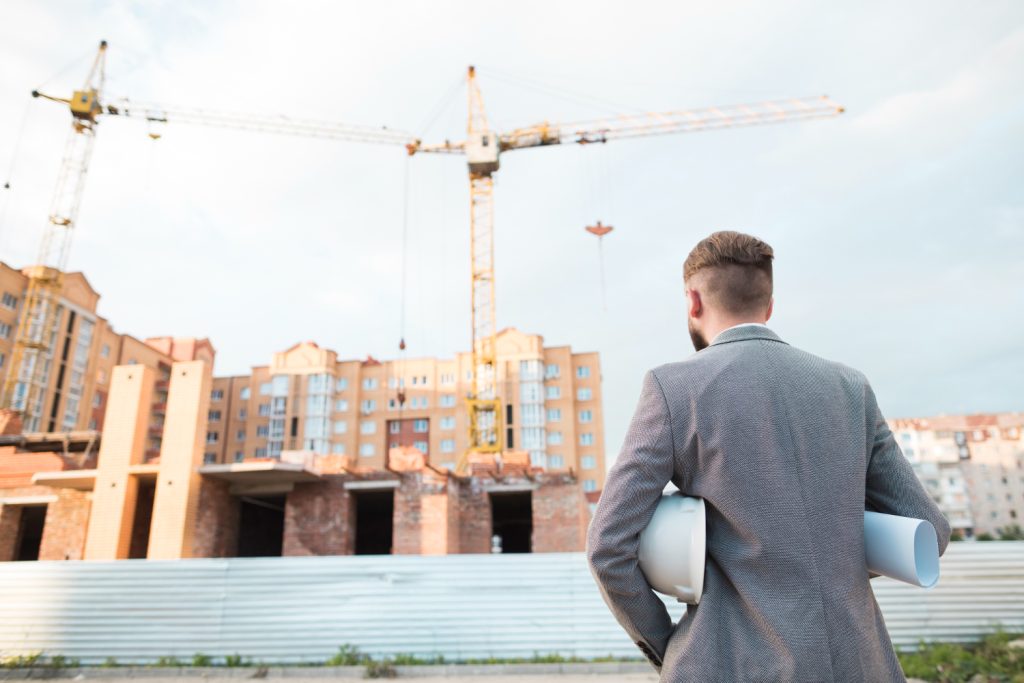 Man in suit observing construction site.